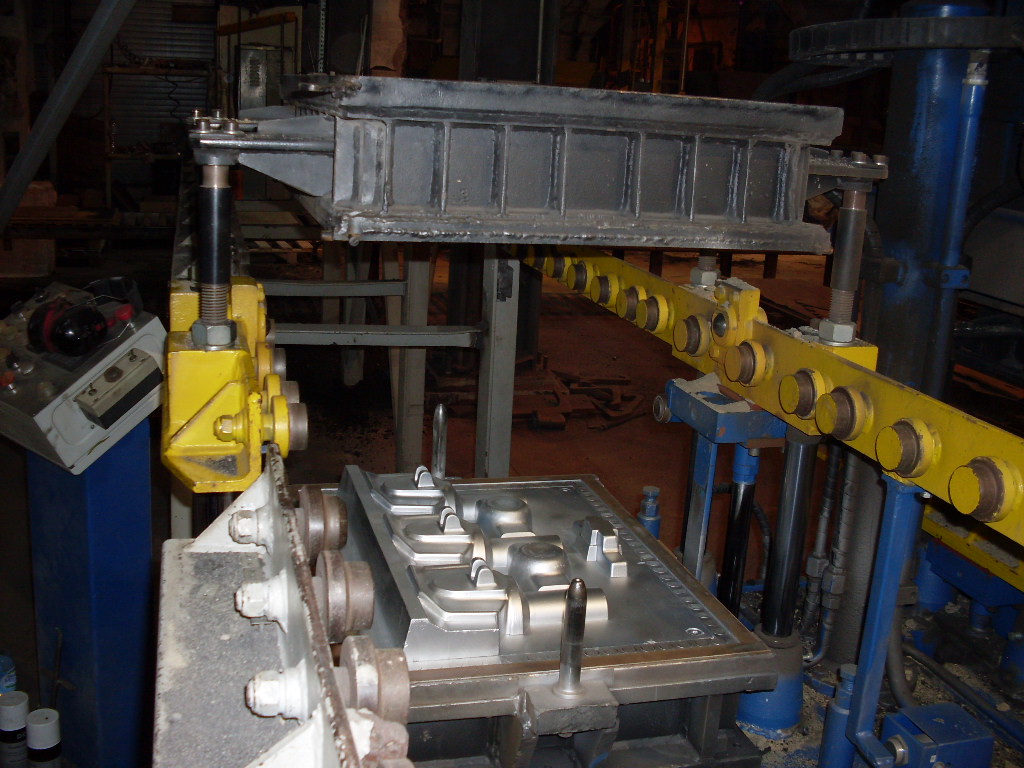 Obraz przedstawia maszynę wykorzystywaną do produkcji odlewów z metali.